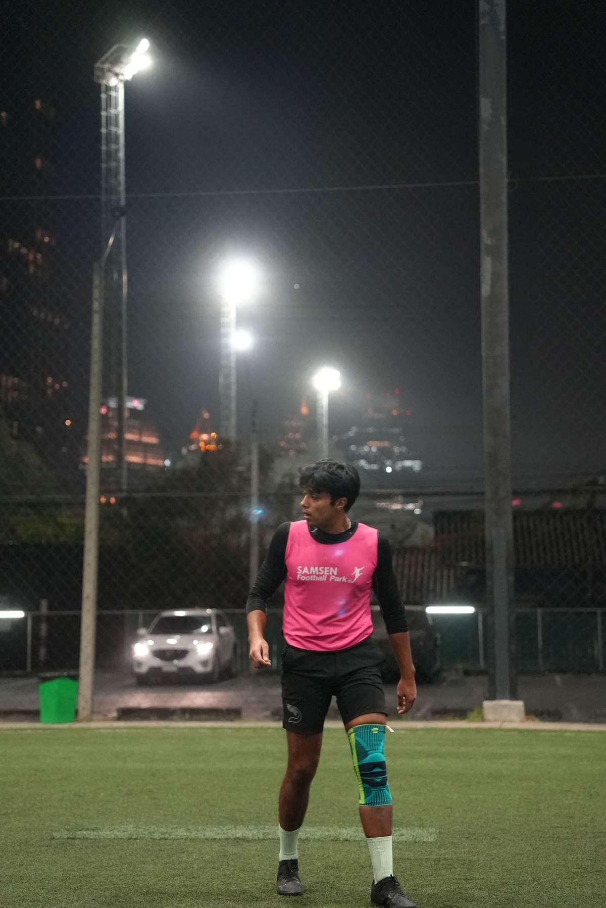 Evening pickup football game under floodlights at POLO Football Park near Phloen Chit BTS station in Bangkok